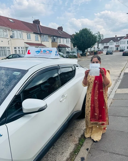 Successful learner celebrating a practical driving test pass beside a Syed’s Driving School tuition car