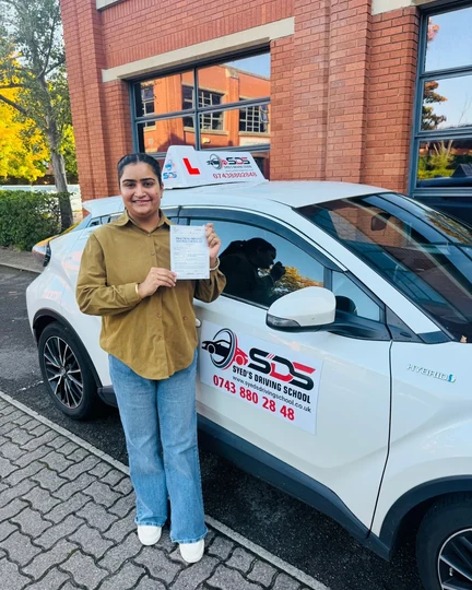 Successful learner celebrating a practical driving test pass beside a Syed’s Driving School tuition car
