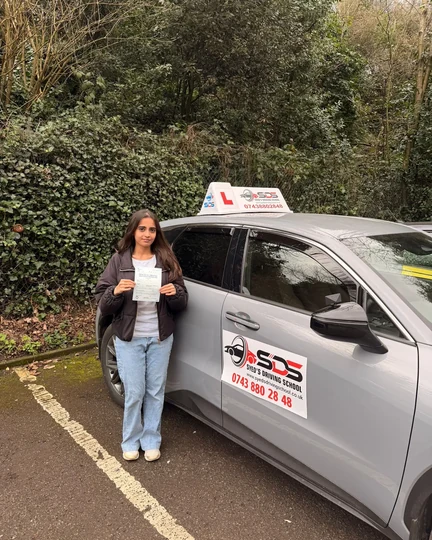 Successful learner celebrating a practical driving test pass beside a Syed’s Driving School tuition car